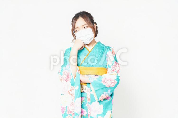 マスクをつけて考え事をする振袖を着た女性 女性,マスク,考えるの写真素材