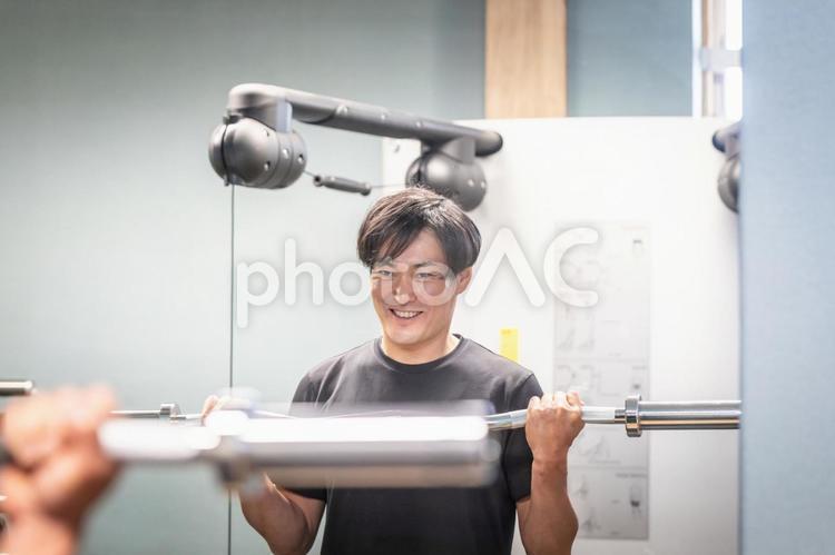 バーベルのシャフトでフォームをチェックする男性（笑顔） バーベル,筋トレ,シャフトの写真素材
