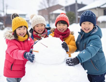 雪だるまを作って喜ぶ子供の冬の屋外風景の写真