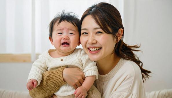 泣いている赤ちゃんを抱っこする笑顔の母親 泣いている赤ちゃんを抱っこする笑顔の母親の写真