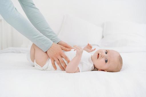 カメラ目線の赤ちゃんのお腹を触る手 カメラ目線の赤ちゃんのお腹を触る手 赤ちゃん,かわいい,仰向けの写真素材