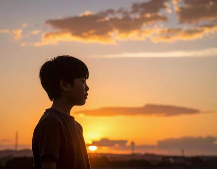 夕焼けの空を見つめる日本人の少年 夕焼けの空を見つめる日本人の少年の写真