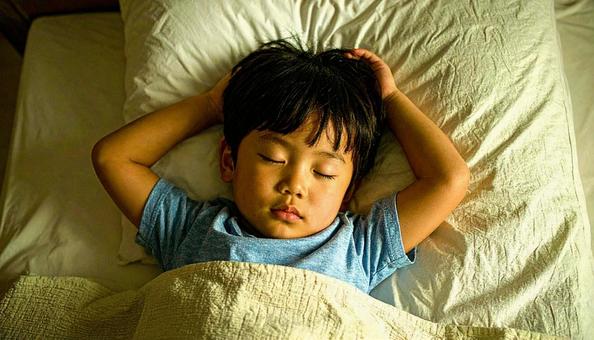 両手をあげて熟睡する男の子 両手をあげて熟睡する男の子の写真