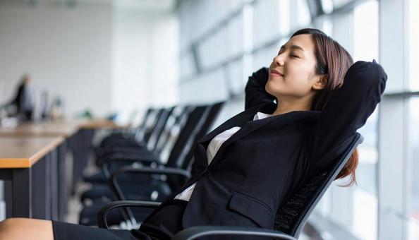 オフィスで目を閉じリラックスする女性社員 オフィスで目を閉じリラックスする女性社員の写真