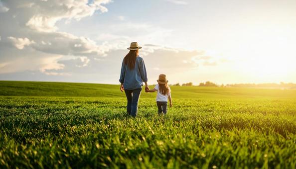草原を歩く親子の後ろ姿の写真