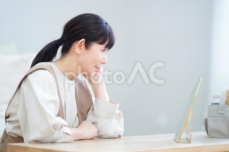 鏡を見つめて肌をチェックする中年女性の横顔 主婦,中年,シニアの写真素材