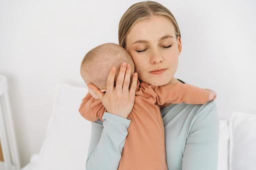 目を瞑り赤ちゃんを抱く女性 目を瞑り赤ちゃんを抱く女性 親子,母子,赤ちゃんの写真素材