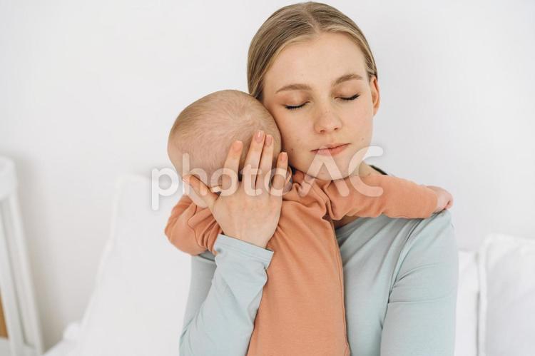 目を瞑り赤ちゃんを抱く女性 親子,母子,赤ちゃんの写真素材