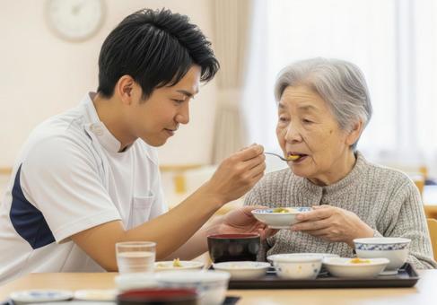 男性介護士が高齢女性に食事介助する場面 男性介護士が高齢女性に食事介助する場面の写真