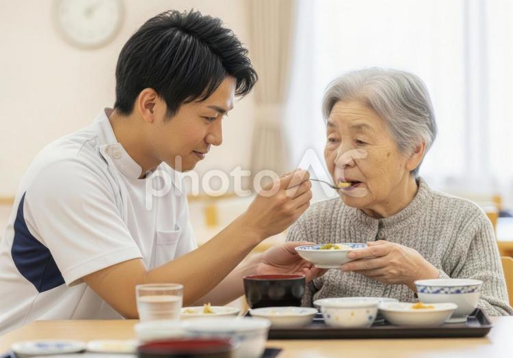 男性介護士が高齢女性に食事介助する場面 介護士,高齢者,食事介助の写真素材