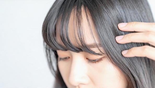 生え際を気にする女性 生え際を気にする女性の写真