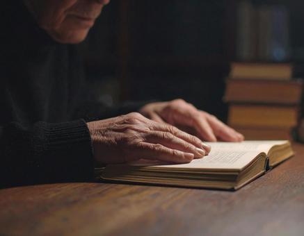 本に手を置く年老いた手のアップの写真