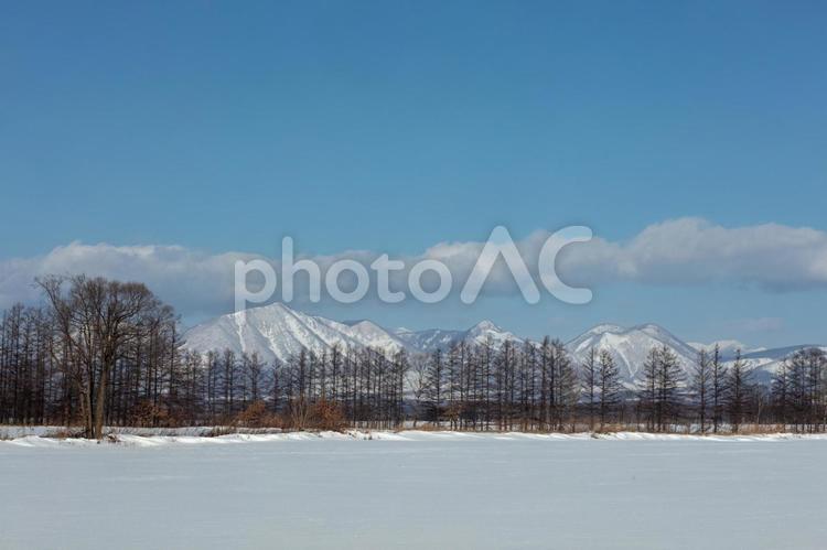 然別の山並みと冬の牧場 雪原,青空,雪の写真素材
