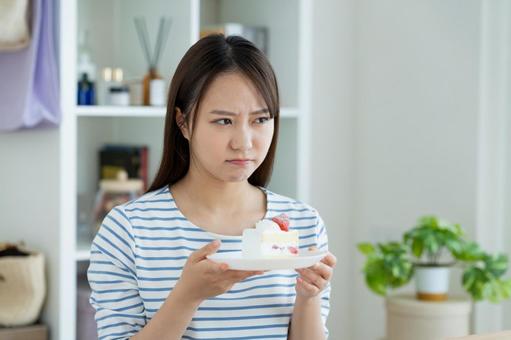 ケーキで悩む若い女性 ダイエット,ケーキ,悩むの写真素材