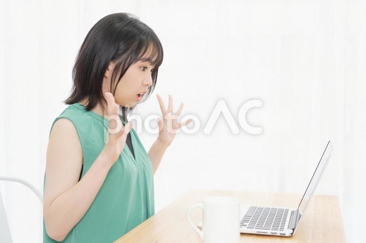 PCを使いながら驚いている若い女性 パソコン,驚く,ビックリの写真素材