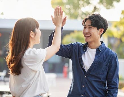 ハイタッチする若い男女 ハイタッチする若い男女の写真