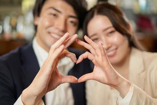 Asian couple making a heart symbol with their fingers Asian couple making a heart symbol with their fingers