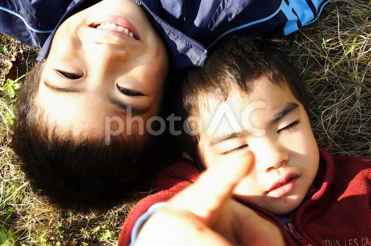 子供が芝生に転んでいる二人 子供,手のひら,寝転ぶの写真素材