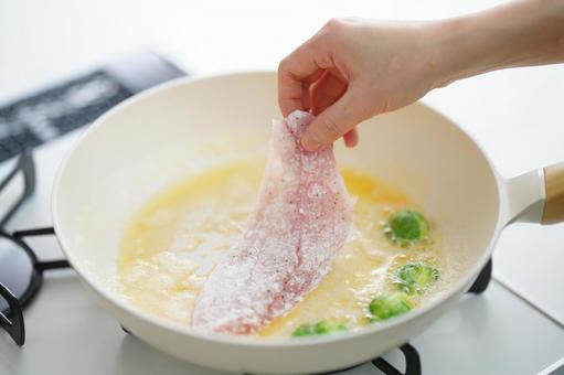 フライパンに魚をのせる手 フライパンに魚をのせる手 魚,料理,フライパンの写真素材