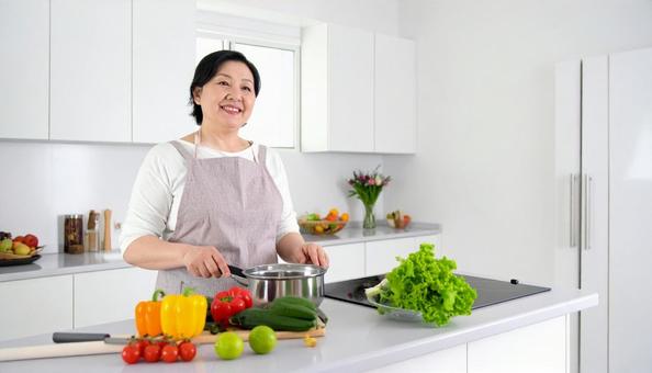 キッチンで調理する笑顔のミドル女性 キッチンで調理する笑顔のミドル女性の写真