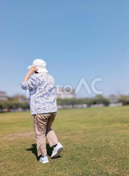 風に飛ばされそうな帽子に手を当ててる人 空,女性,帽子の写真素材