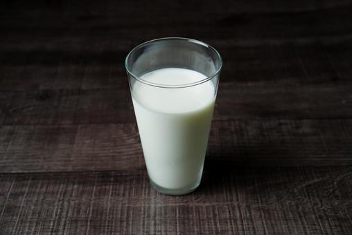 木製テーブルに置かれた牛乳の写真
