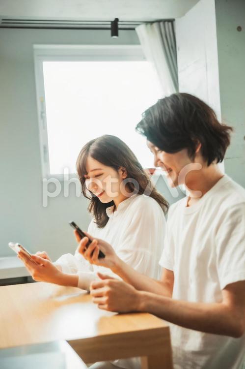 部屋でスマホを使う男女（横顔） スマホ,カップル,夫婦の写真素材