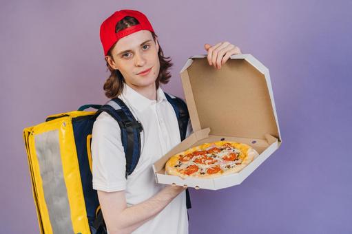 ピザを見せるフードデリバリーの男性（紫背景） 配達,フードデリバリー,デリバリーの写真素材
