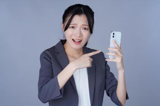 スマホを指さしているスーツを着た女性 女性,スマートフォン,持つの写真素材