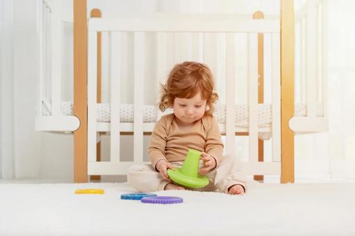 緑色の玩具を持ち見つめるくせ毛の子 緑色の玩具を持ち見つめるくせ毛の子 赤ちゃん,かわいい,お座りの写真素材