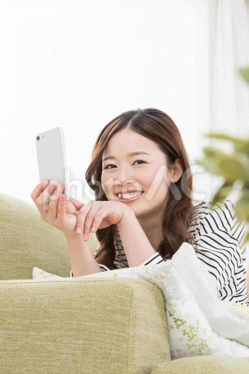 ソファーでスマホを使う女性 スマートフォン,女性,検索の写真素材
