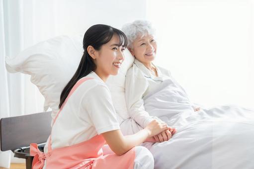 寝ているシニア女性を介護をする介護士 介護,介護士,シニアの写真素材