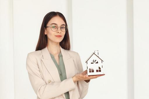 手に家の模型を持ち笑顔を浮かべる女性スタッフ 保険業,事務職,接客業の写真素材