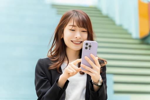 スマホを使う笑顔の女性・ビジネスウーマン スマホを使う笑顔の女性・ビジネスウーマン 女性,スマホ,スマートフォンの写真素材