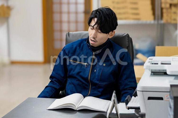 やる気がなくため息をつく作業着の男性 ビジネス,ビジネスマン,男の写真素材