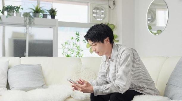 リビングでスマートフォンを見る男性 男性,スマホ,スマートフォンの写真素材