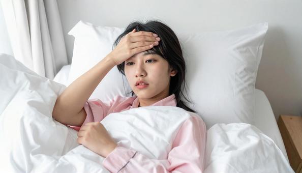 発熱して寝込んで体温計を見る女の子 発熱して寝込んで体温計を見る女の子の写真
