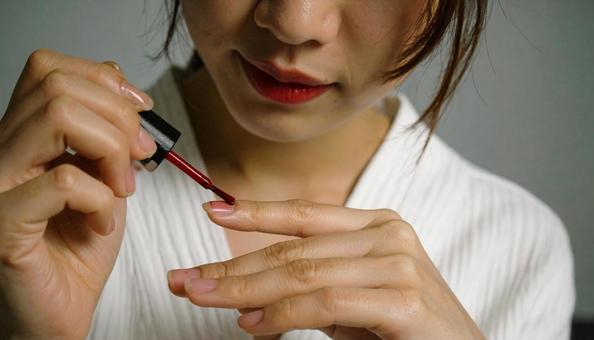 指にネイルを塗る女性の手元 指にネイルを塗る女性の手元の写真
