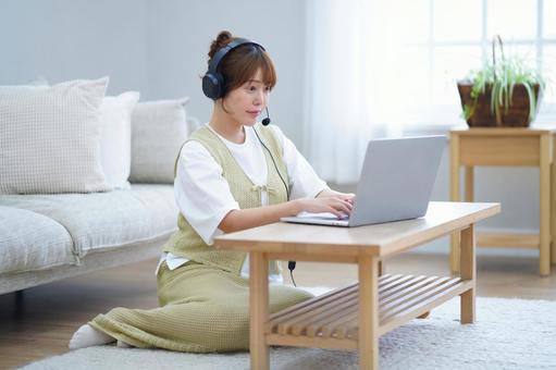 ヘッドセットをしてパソコンをしている女性 女性,ノートパソコン,見るの写真素材
