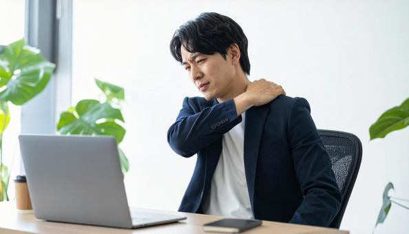 デスクワークで肩こりに悩むビジネスマン デスクワークで肩こりに悩むビジネスマンの写真