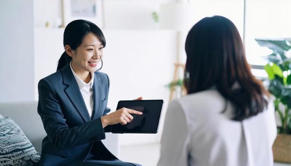 タブレットを使って説明する女性営業マン タブレットを使って説明する女性営業マンの写真
