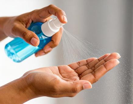 手のひらをスプレーで消毒の写真