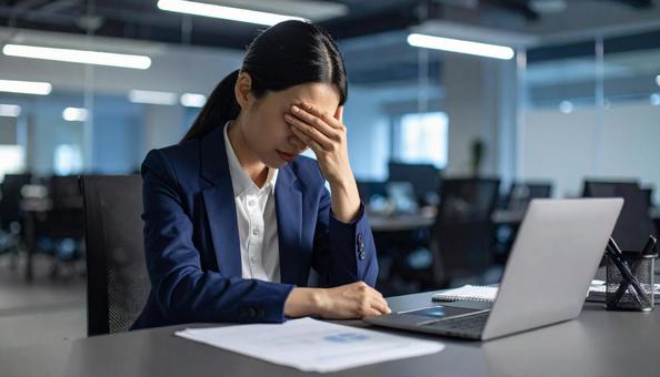 仕事で失敗して悩む女性社員 仕事で失敗して悩む女性社員の写真