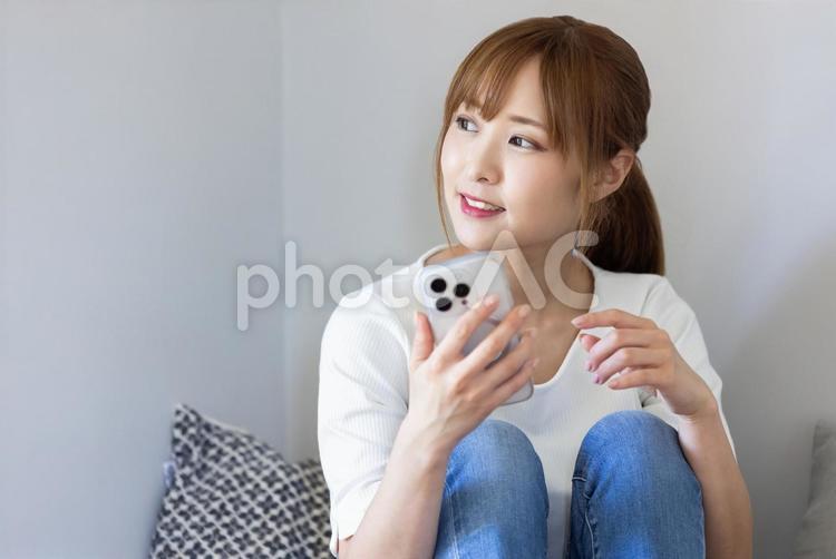 ソファでスマホを見てくつろぐ女性 リビング,女性,マグカップの写真素材