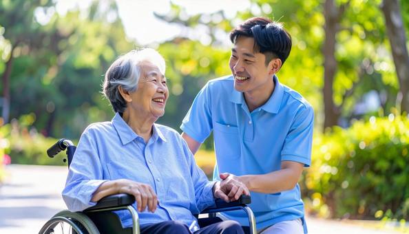散歩する車椅子の高齢女性と男性介護士 散歩する車椅子の高齢女性と男性介護士の写真