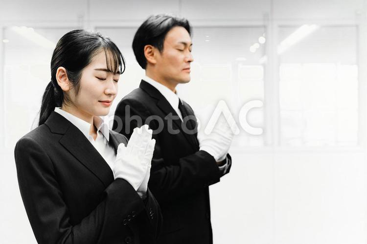 白手袋をつけて合掌するスーツ姿の男女 葬祭ディレクター,白手袋,礼服の写真素材