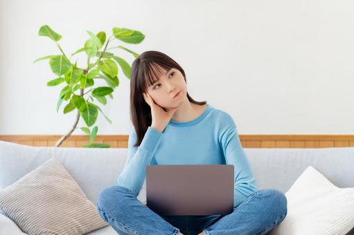 ソファでパソコンを使いながら考える女性 女性,パソコン,ノートパソコンの写真素材