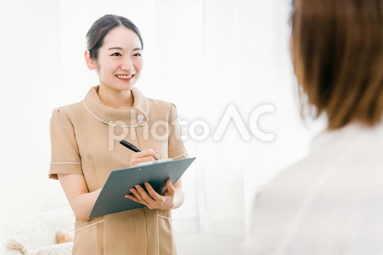 来店したお客様にヒヤリングをする女性 受付,エステサロン,ネイルサロンの写真素材