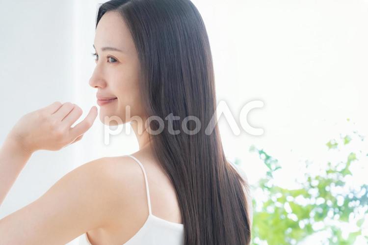 緑の中でスキンケアをする若い女性 ビューティー,女性,スキンケアの写真素材