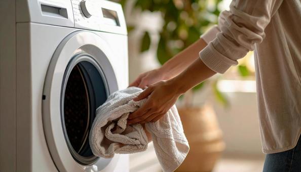 洗濯機から洗濯物を取り出す女性の手 洗濯機から洗濯物を取り出す女性の手の写真